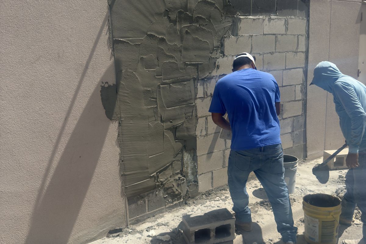 Crew applying stucco coats over the new block